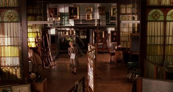 Movie still from “Mona Lisa Smile” (2003), directed by Mike Newell – A woman in a room with many paintings on the walls; Wide shot, Low angle
