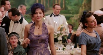 Movie still from “Mona Lisa Smile” (2003), directed by Mike Newell – A woman in a purple dress standing in front of a group of people; Medium shot, Over the shoulder angle