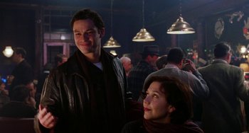 Movie still from “Mona Lisa Smile” (2003), directed by Mike Newell – A man and a woman are standing in front of a group of diners; Medium shot, Over the shoulder angle