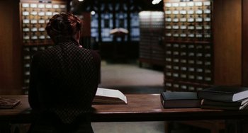 Movie still from “Mona Lisa Smile” (2003), directed by Mike Newell – A woman sitting at a wooden table with a book; Medium shot, High angle