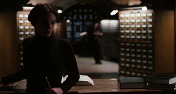 Movie still from “Mona Lisa Smile” (2003), directed by Mike Newell – A woman sitting at a table writing on a notebook; Medium shot, Low angle