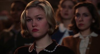 Movie still from “Mona Lisa Smile” (2003), directed by Mike Newell – A young woman with short blonde hair wearing a black dress; Close Up shot, Over the shoulder angle