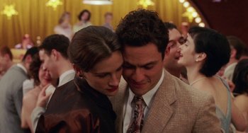 Movie still from “Mona Lisa Smile” (2003), directed by Mike Newell – A man and a woman hugging in a crowd of people; Close Up shot, Over the shoulder angle