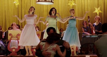 Movie still from “Mona Lisa Smile” (2003), directed by Mike Newell – A group of women singing in front of an audience; Medium shot, Low angle