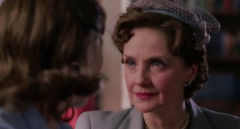 Movie still from “Mona Lisa Smile” (2003), directed by Mike Newell – An older woman wearing a gray suit and a hat; Close Up shot, Over the shoulder angle