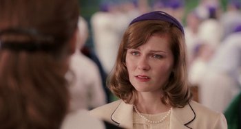 Movie still from “Mona Lisa Smile” (2003), directed by Mike Newell – A woman wearing a purple hat and a white jacket; Close Up shot, Over the shoulder angle