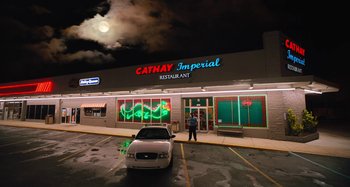 Movie still from “Mona Lisa and the Blood Moon” (2021), directed by Ana Lily Amirpour – A man standing in front of a restaurant at night; Extreme Wide shot, Low angle