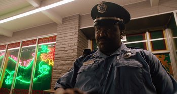 Movie still from “Mona Lisa and the Blood Moon” (2021), directed by Ana Lily Amirpour – A man in a police officer's uniform is smiling; Close Up shot, Over the shoulder angle