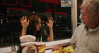 Movie still from “Mona Lisa and the Blood Moon” (2021), directed by Ana Lily Amirpour – A woman sitting at a table in front of an open window; Medium shot, Over the shoulder angle