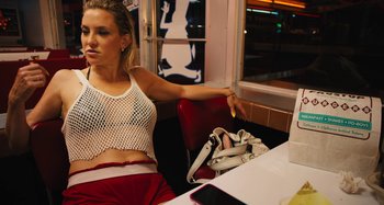 Movie still from “Mona Lisa and the Blood Moon” (2021), directed by Ana Lily Amirpour – A woman sitting at a table in front of a window; Medium shot, Low angle