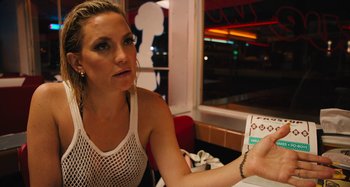 Movie still from “Mona Lisa and the Blood Moon” (2021), directed by Ana Lily Amirpour – A woman sitting at a table with a cigarette in her hand; Close Up shot, Over the shoulder angle