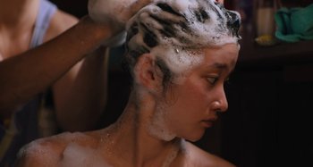Movie still from “Mona Lisa and the Blood Moon” (2021), directed by Ana Lily Amirpour – A woman is getting her hair brushed by another woman; Close Up shot, Over the shoulder angle