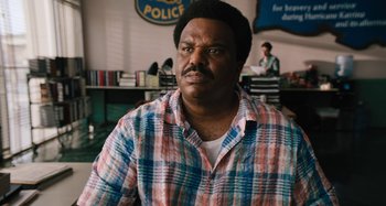 Movie still from “Mona Lisa and the Blood Moon” (2021), directed by Ana Lily Amirpour – A man in a plaid shirt in front of a police sign; Close Up shot, Over the shoulder angle