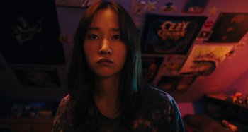Movie still from “Mona Lisa and the Blood Moon” (2021), directed by Ana Lily Amirpour – A young asian woman with long black hair in a room; Close Up shot, Low angle