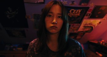 Movie still from “Mona Lisa and the Blood Moon” (2021), directed by Ana Lily Amirpour – A young woman with long black hair is looking at the camera; Close Up shot, High angle