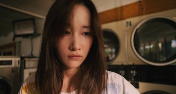 Movie still from “Mona Lisa and the Blood Moon” (2021), directed by Ana Lily Amirpour – A woman with long brown hair is looking at the camera; Close Up shot, Low angle