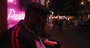 Movie still from “Mona Lisa and the Blood Moon” (2021), directed by Ana Lily Amirpour – A man with a beard is holding a plate of food; Close Up shot, Low angle
