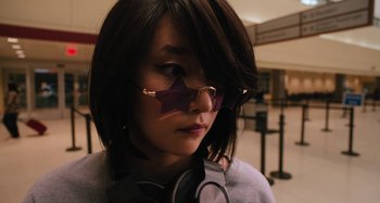 Movie still from “Mona Lisa and the Blood Moon” (2021), directed by Ana Lily Amirpour – A woman wearing glasses and a star shaped mirror on her face; Close Up shot, Over the shoulder angle