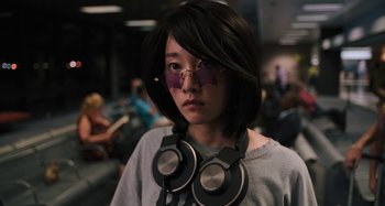 Movie still from “Mona Lisa and the Blood Moon” (2021), directed by Ana Lily Amirpour – A person with headphones around their neck and glasses on; Close Up shot, Low angle
