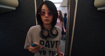 Movie still from “Mona Lisa and the Blood Moon” (2021), directed by Ana Lily Amirpour – A young woman wearing sunglasses and holding a cell phone; Medium shot, Over the shoulder angle