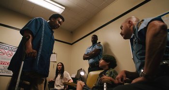 Movie still from “Mona Lisa and the Blood Moon” (2021), directed by Ana Lily Amirpour – A group of people sitting in a room; Medium shot, Over the shoulder angle