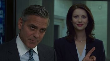 Movie still from “Money Monster” (2016), directed by Jodie Foster – A man and a woman standing next to each other; Medium shot, Low angle