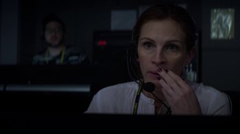 Movie still from “Money Monster” (2016), directed by Jodie Foster – A woman wearing a headset in front of a computer screen; Close Up shot, Low angle