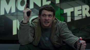 Movie still from “Money Monster” (2016), directed by Jodie Foster – A man holding a remote control in his hand; Medium shot, Low angle