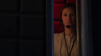 Movie still from “Money Monster” (2016), directed by Jodie Foster – A woman wearing a headset looking out a window; Medium shot, Low angle