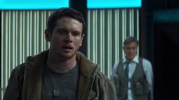 Movie still from “Money Monster” (2016), directed by Jodie Foster – A man standing next to another man in front of a building; Medium shot, Over the shoulder angle