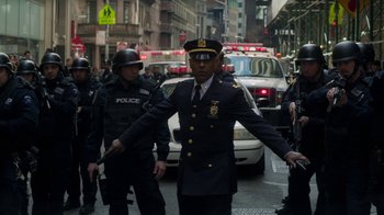 Movie still from “Money Monster” (2016), directed by Jodie Foster – A man in a police uniform walking down a street; Medium shot, Over the shoulder angle