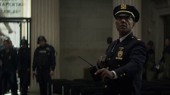 Movie still from “Money Monster” (2016), directed by Jodie Foster – A man in a police uniform holding a walkie talkie; Medium shot, Low angle