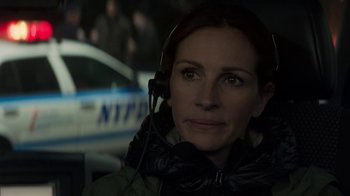 Movie still from “Money Monster” (2016), directed by Jodie Foster – A woman wearing a headset in front of a police car; Close Up shot, Over the shoulder angle