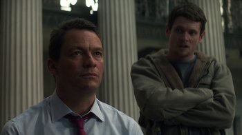 Movie still from “Money Monster” (2016), directed by Jodie Foster – Two men standing next to each other in front of a building; Medium shot, Low angle