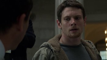 Movie still from “Money Monster” (2016), directed by Jodie Foster – A young man in a brown jacket looking at the camera; Close Up shot, Over the shoulder angle