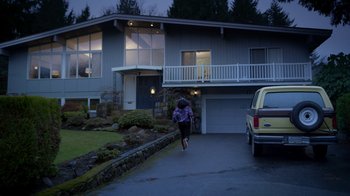 Movie still from “Monster High: The Movie” (2022), directed by Todd Holland – A woman walking down the street in front of a house; Extreme Wide shot, Over the shoulder angle