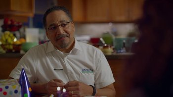 Movie still from “Monster High: The Movie” (2022), directed by Todd Holland – A man sitting at a table in front of a counter; Close Up shot, Over the shoulder angle