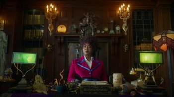 Movie still from “Monster High: The Movie” (2022), directed by Todd Holland – A woman sitting in front of a table with candles; Medium shot, Low angle