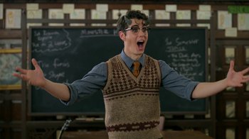 Movie still from “Monster High: The Movie” (2022), directed by Todd Holland – A young man wearing glasses and a sweater vest; Medium shot, Over the shoulder angle