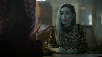 Movie still from “Monster High: The Movie” (2022), directed by Todd Holland – A woman sitting at a table with a cell phone in front of her face; Medium shot, Over the shoulder angle