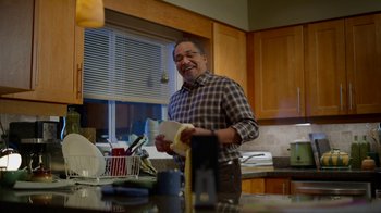 Movie still from “Monster High: The Movie” (2022), directed by Todd Holland – A man standing in a kitchen holding a napkin; Medium shot, Low angle