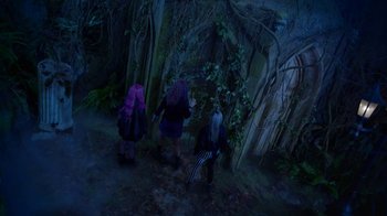 Movie still from “Monster High: The Movie” (2022), directed by Todd Holland – Three people are walking through the woods at night; Extreme Wide shot, High angle