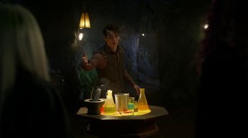 Movie still from “Monster High: The Movie” (2022), directed by Todd Holland – A man standing in front of a table holding a lamp; Medium shot, Over the shoulder angle