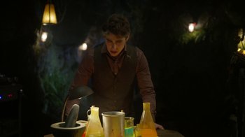 Movie still from “Monster High: The Movie” (2022), directed by Todd Holland – A man standing in front of a table filled with drinks; Medium shot, Over the shoulder angle