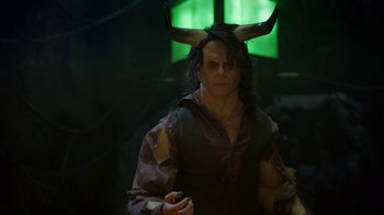 Movie still from “Monster High: The Movie” (2022), directed by Todd Holland – A man with horns is standing in a dark room; Medium shot, Over the shoulder angle