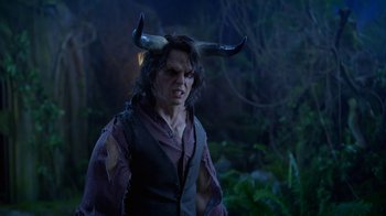 Movie still from “Monster High: The Movie” (2022), directed by Todd Holland – A man with horns on his head is standing in the woods; Medium shot, Over the shoulder angle