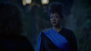 A woman in a black and blue dress looking to her left