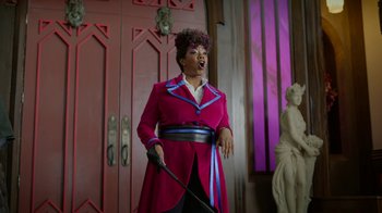 Movie still from “Monster High: The Movie” (2022), directed by Todd Holland – A woman in a pink coat holding a cane; Medium shot, Low angle