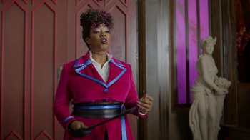 Movie still from “Monster High: The Movie” (2022), directed by Todd Holland – A woman in a pink jacket holding a pan; Medium shot, Over the shoulder angle