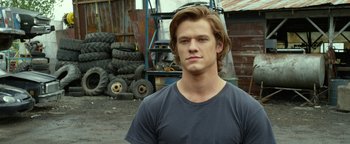 Movie still from “Monster Trucks” (2016), directed by Chris Wedge – A young man standing in front of a pile of tires; Close Up shot, Over the shoulder angle